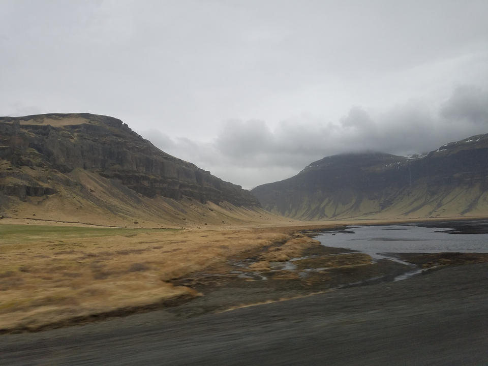 Moody overcast landscape of steep cliffs and a winding river delta on a grey day.