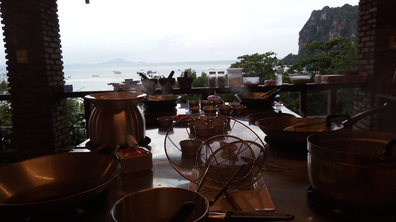 Outdoor cooking area facing the sea, with pots and utensils.