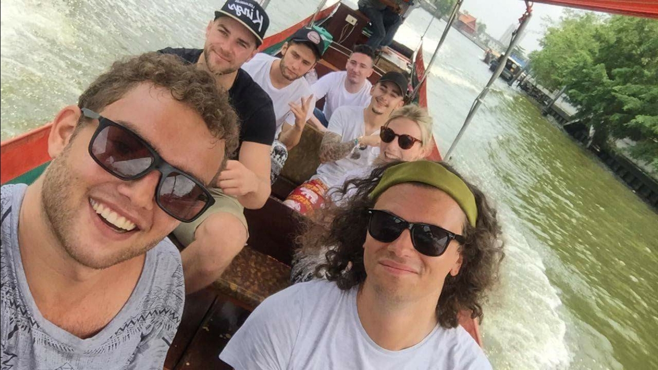Group on a boat ride through a canal with green foliage around.