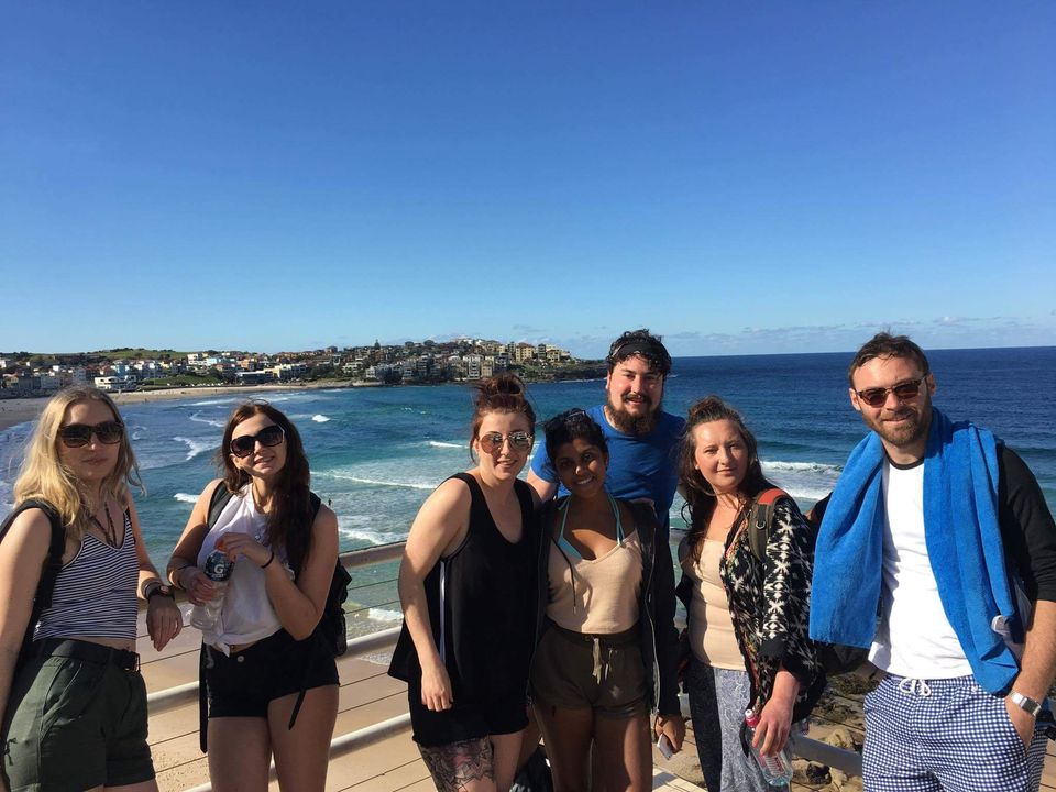 Group of friends posing by the ocean in front of a scenic beach.