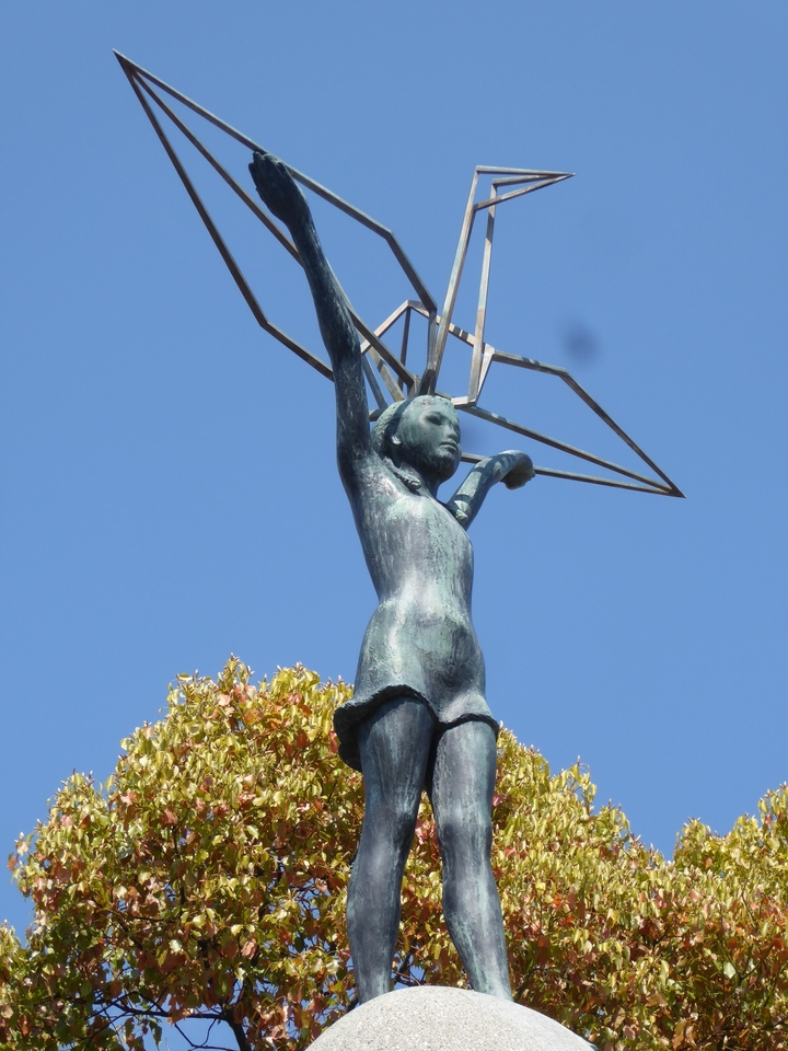 Statue of a figure with a geometric structure above their head.
