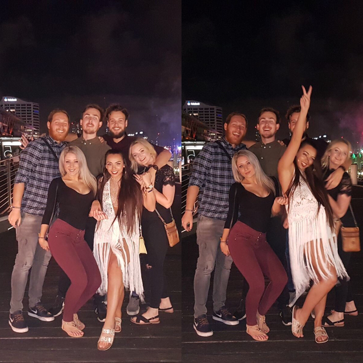 Group of friends posing at night on a boardwalk with colorful lights.