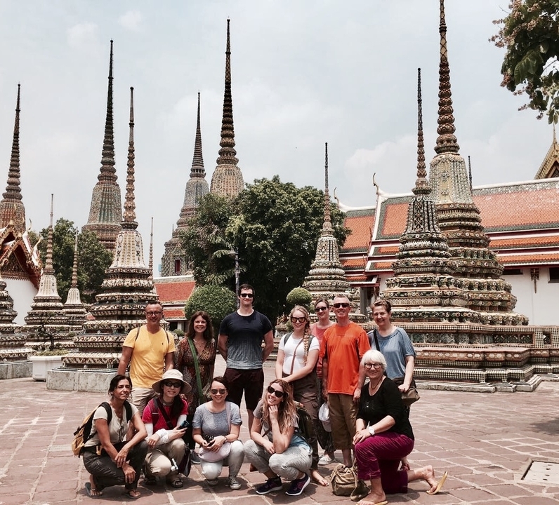 Groupe de personnes dans un temple avec des flèches ornées en arrière-plan.