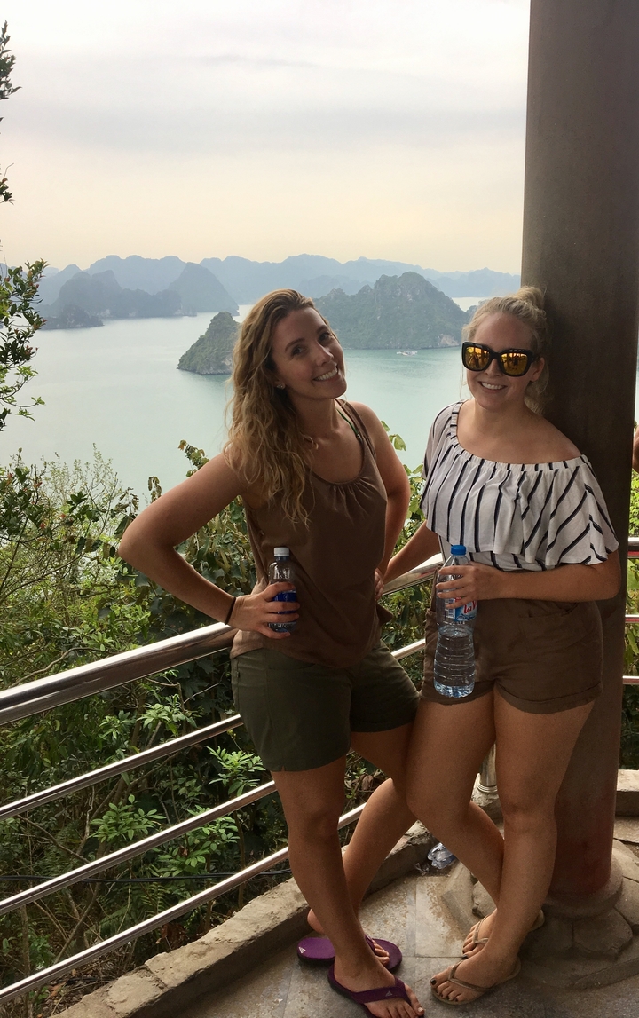 Deux femmes posant avec une vue panoramique de l'eau et des collines.