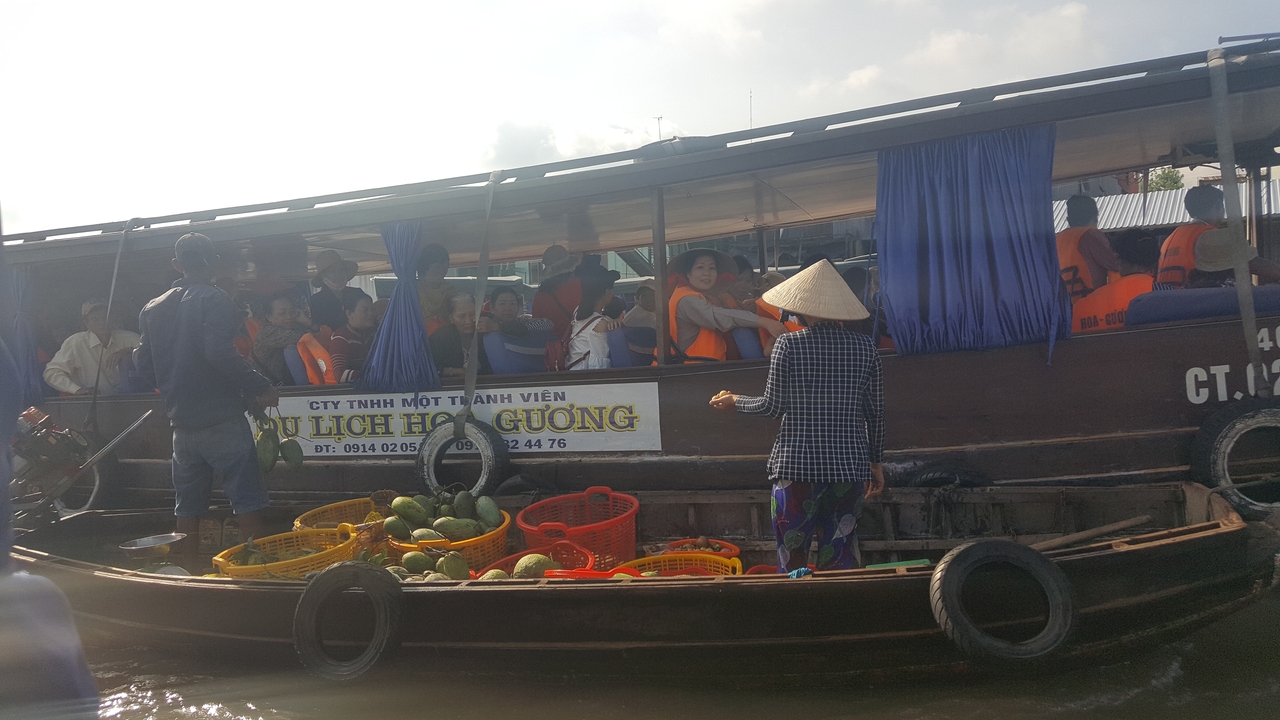 Marché flottant animé avec des bateaux et des paniers de fruits.