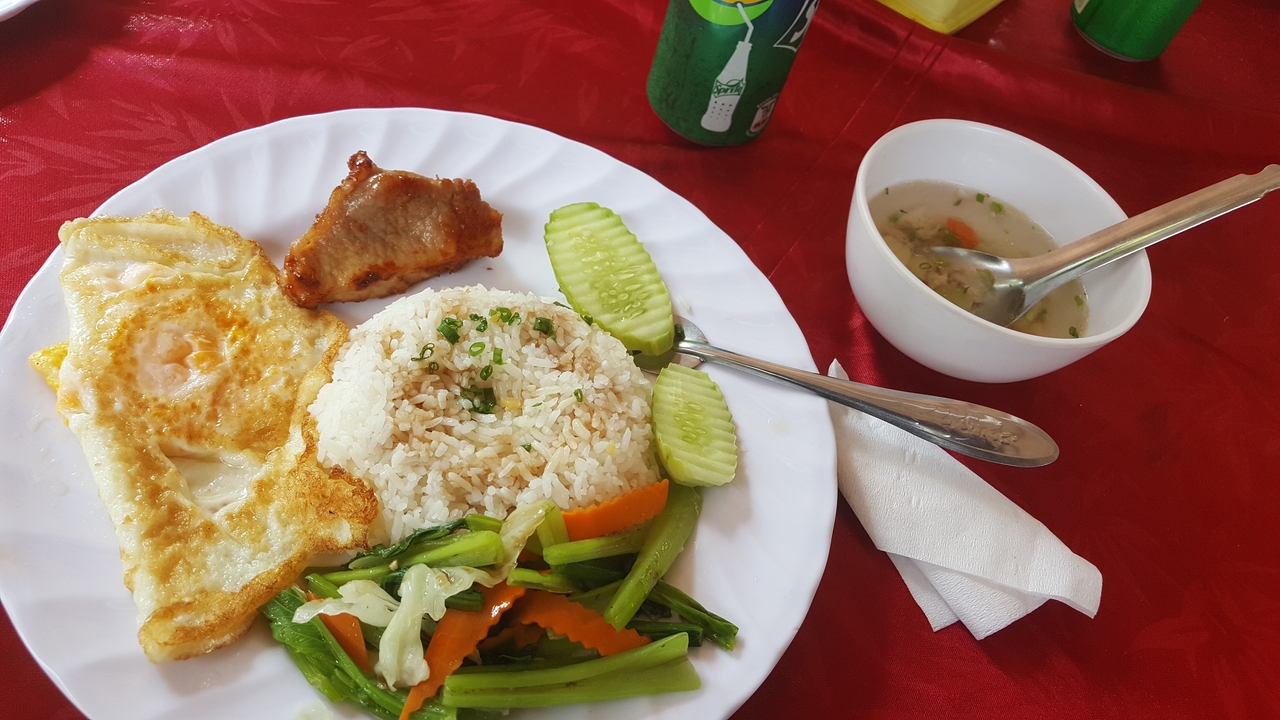 Assiette de nourriture avec du riz, des légumes et de la viande sur une nappe rouge.