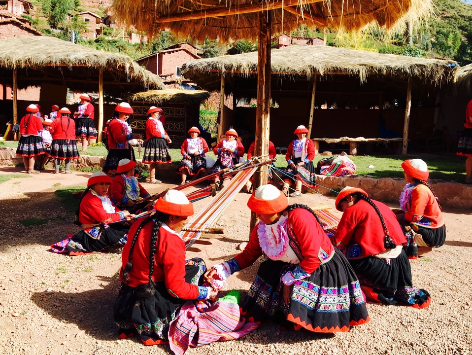Femmes en vêtements traditionnels tissant dans un cadre culturel.
