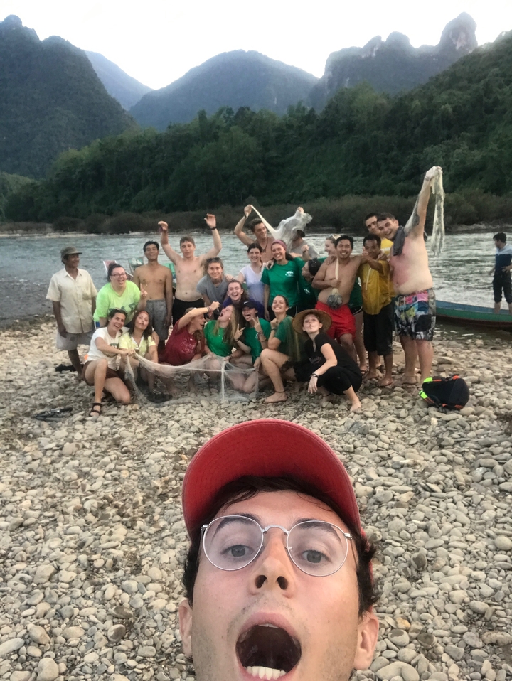 Group of people on a rocky riverbank posing with fishing nets.
