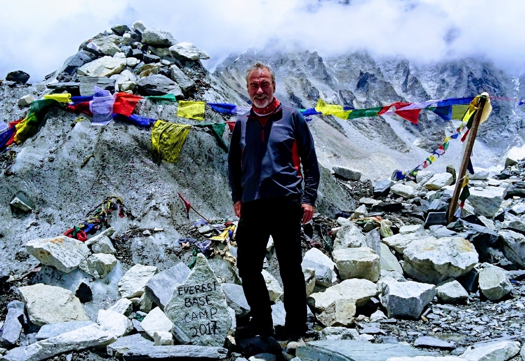 Homme debout au camp de base de l'Everest avec des drapeaux de prière.