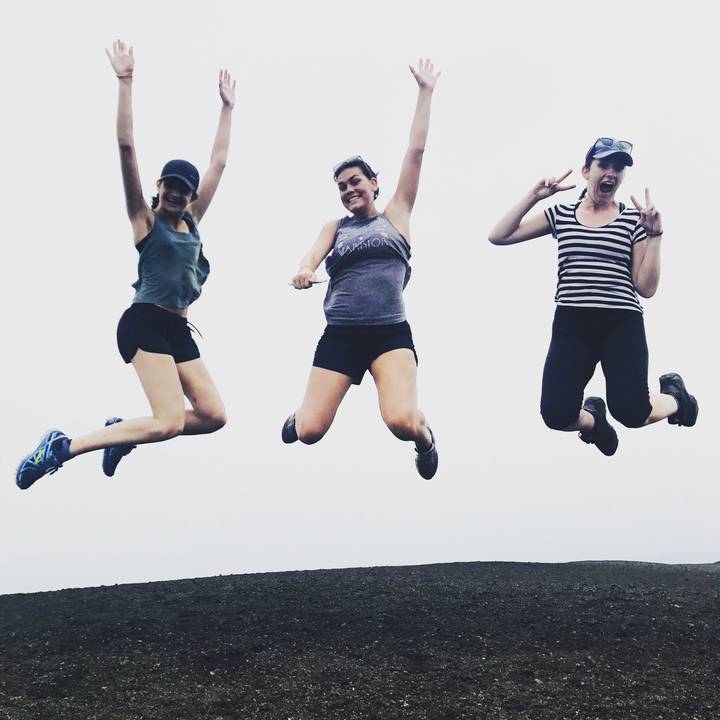 Three women jumping joyfully in the air against a white background.