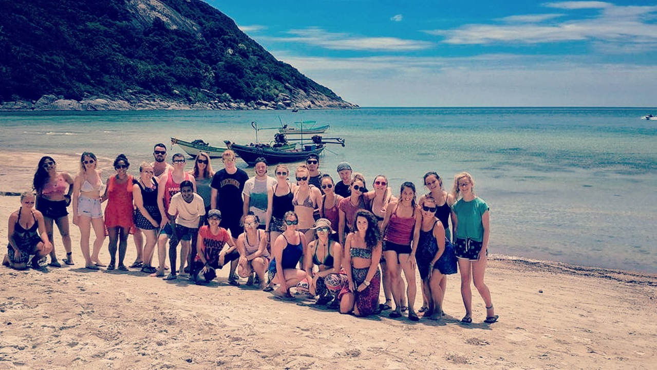 Group of people posing on a beach.