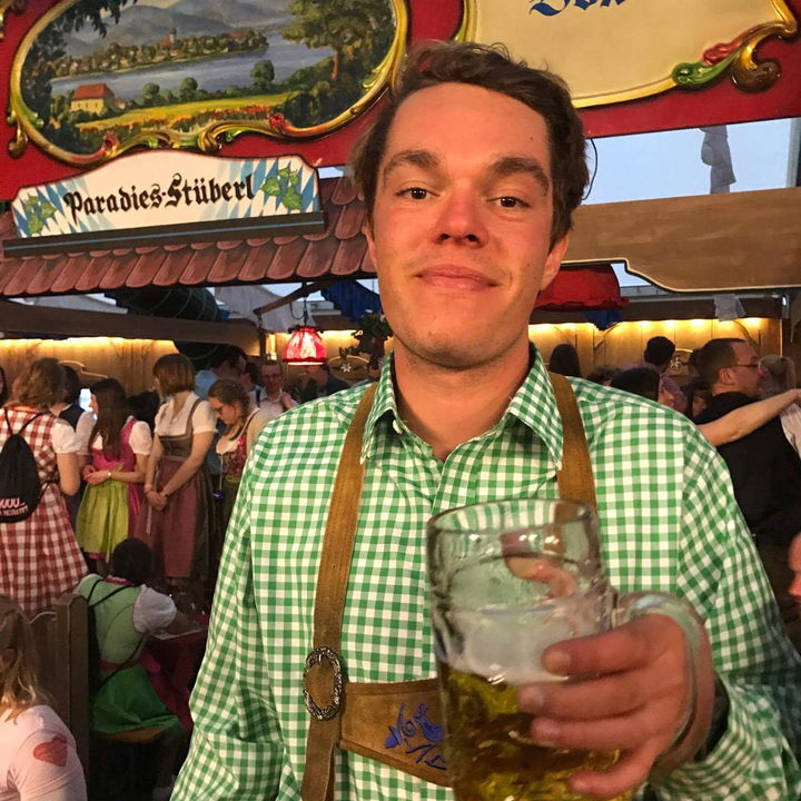 Homme tenant une grande chope de bière lors d'un festival en plein air.