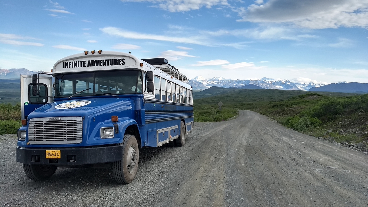 Bus de l'aventure sur une route panoramique avec un paysage montagneux.