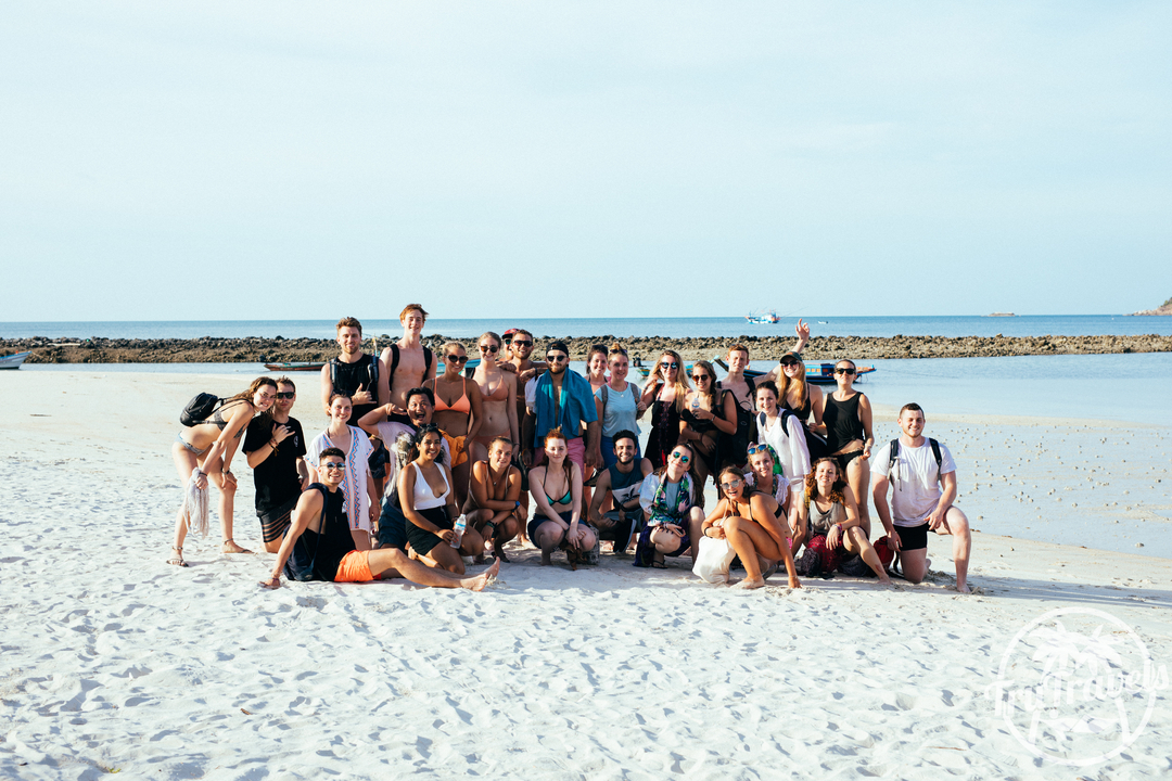 Group of people posing on a beach with a watermark present.