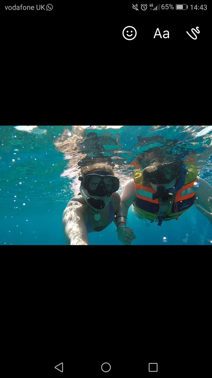 Two people snorkeling underwater in clear blue water.