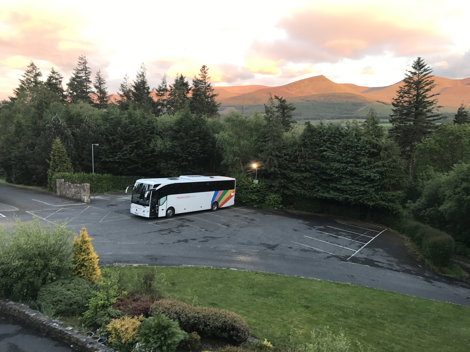Bus garé sur un terrain avec des montagnes pittoresques en arrière-plan.