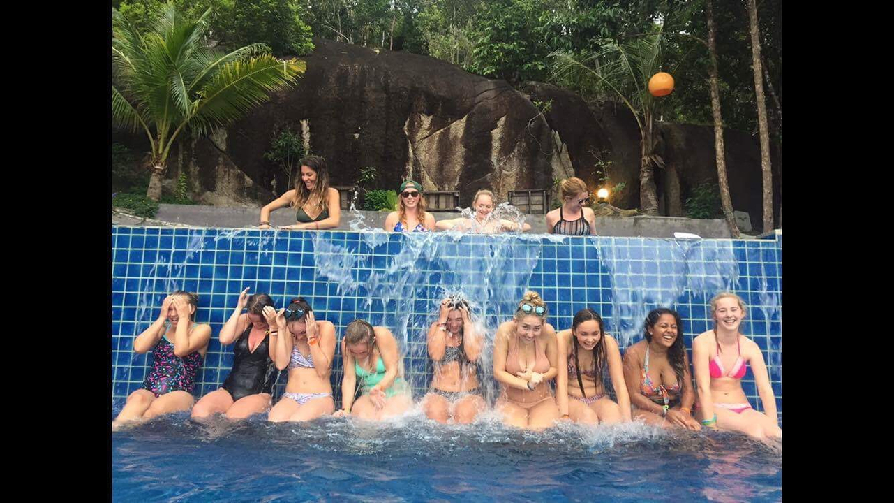Group of people sitting by a pool with water cascading over them.