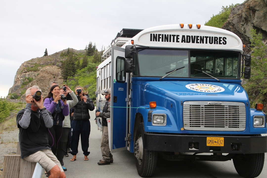 Groupe de personnes avec des appareils photo près d'un bus touristique bleu.