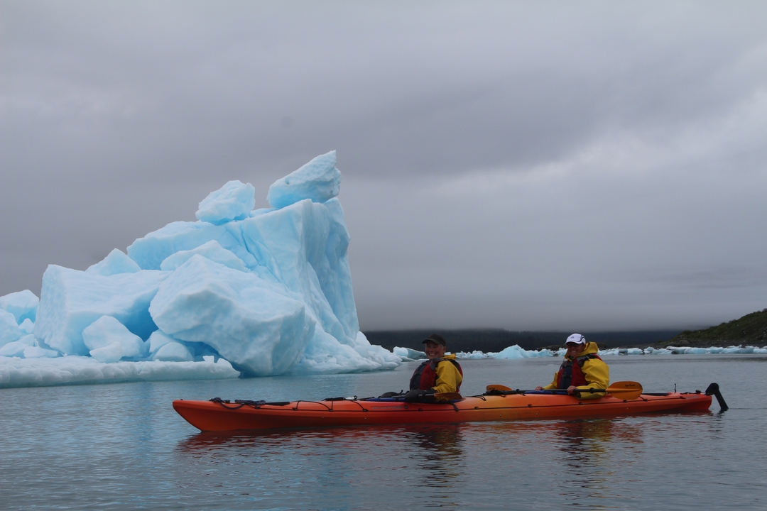 Deux personnes en kayak près d'un iceberg.