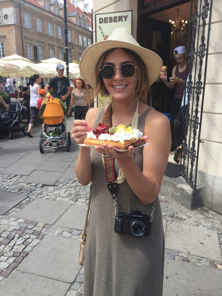 Personne tenant une gaufre avec des garnitures, debout à l'extérieur.