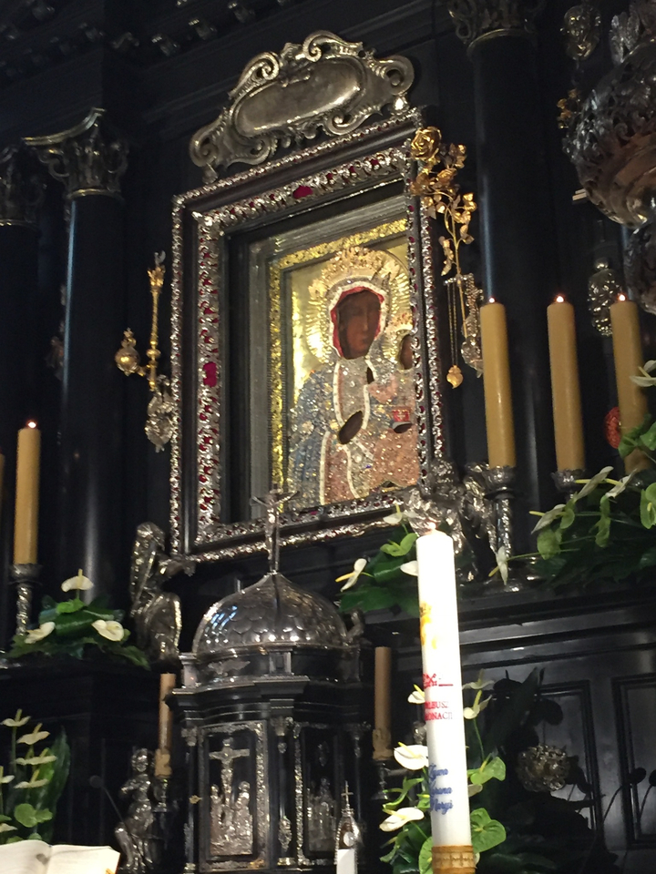 Icône religieuse entourée de bougies et de décorations.