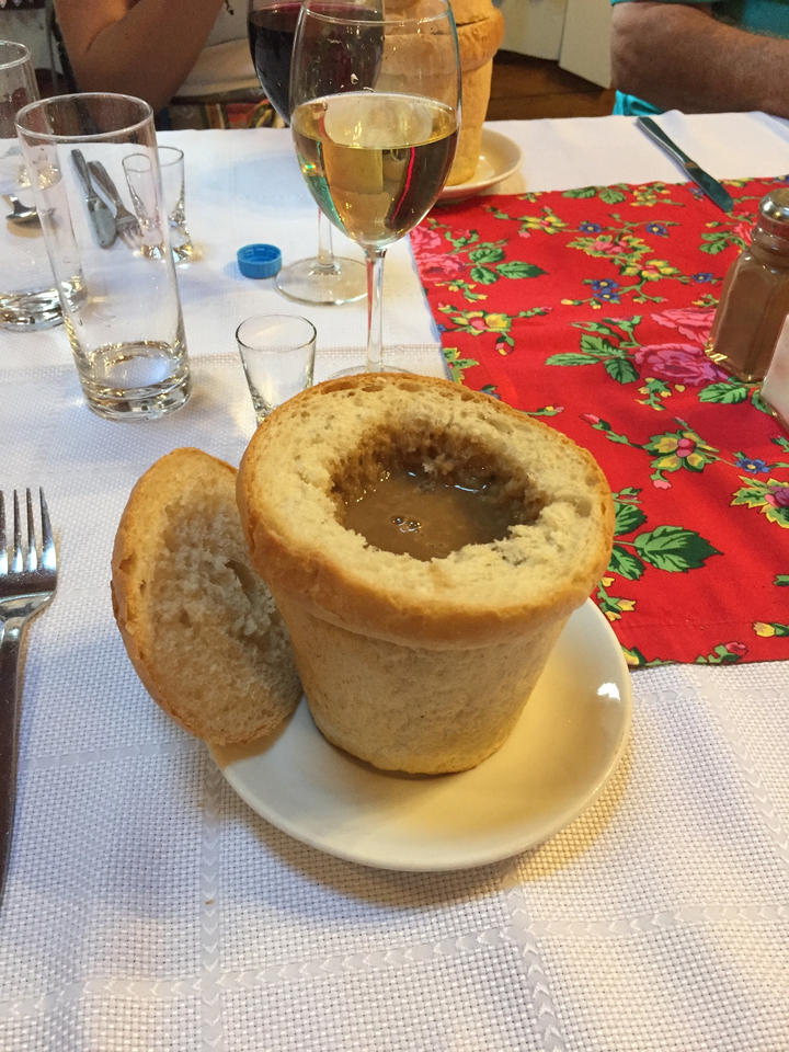 Soupe servie dans un bol de pain sur une table décorée.