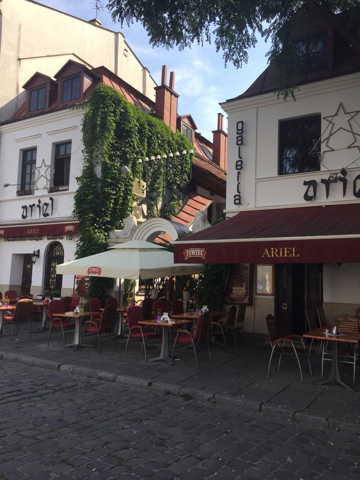 Café en plein air avec une façade en briques rouges et du lierre qui pousse sur les murs.