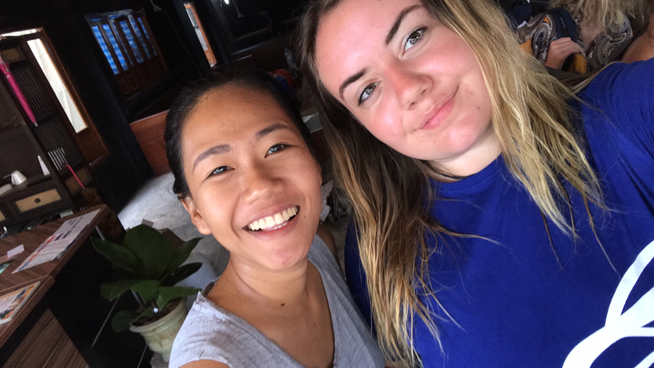 Two women smiling in a brightly lit indoor area.