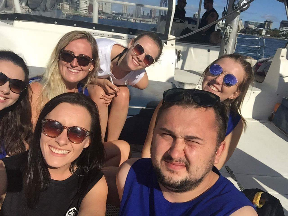 Group of friends sitting on a boat, wearing sunglasses.