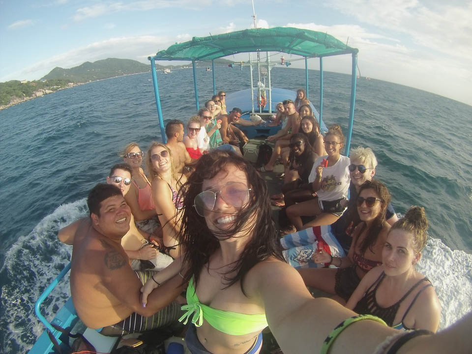 Large group selfie on a speedboat cruising through blue ocean waters