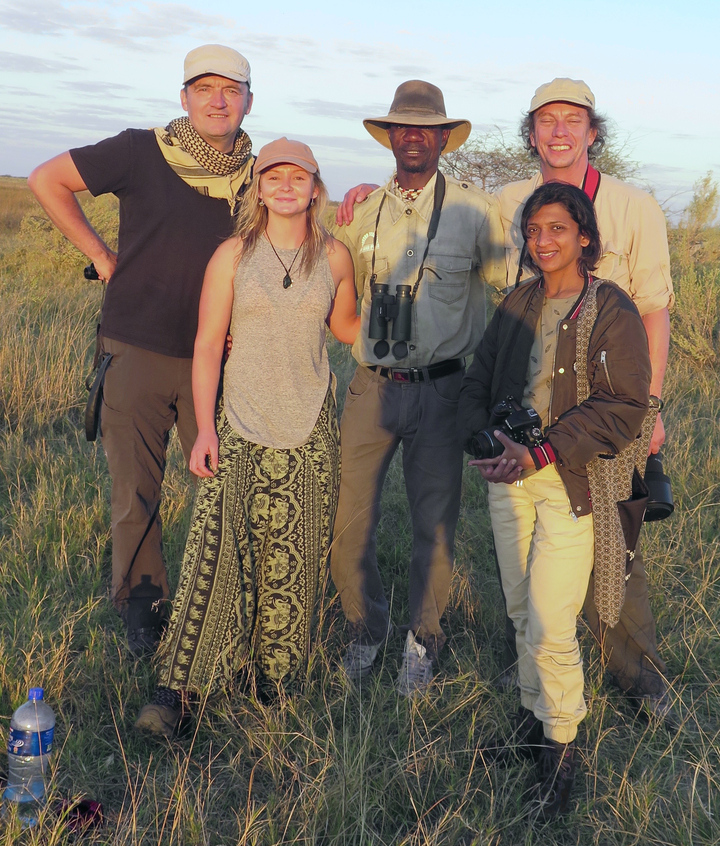 Groupe de personnes posant dans un champ ensoleillé.