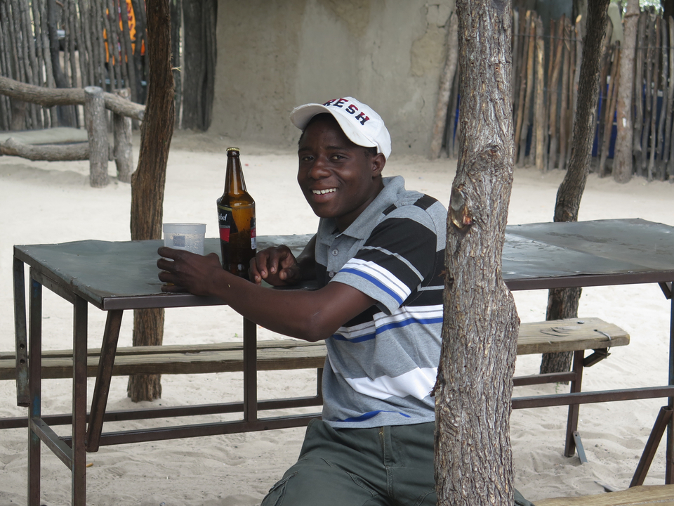 Une personne sourit alors qu'elle est assise à une table en plein air.