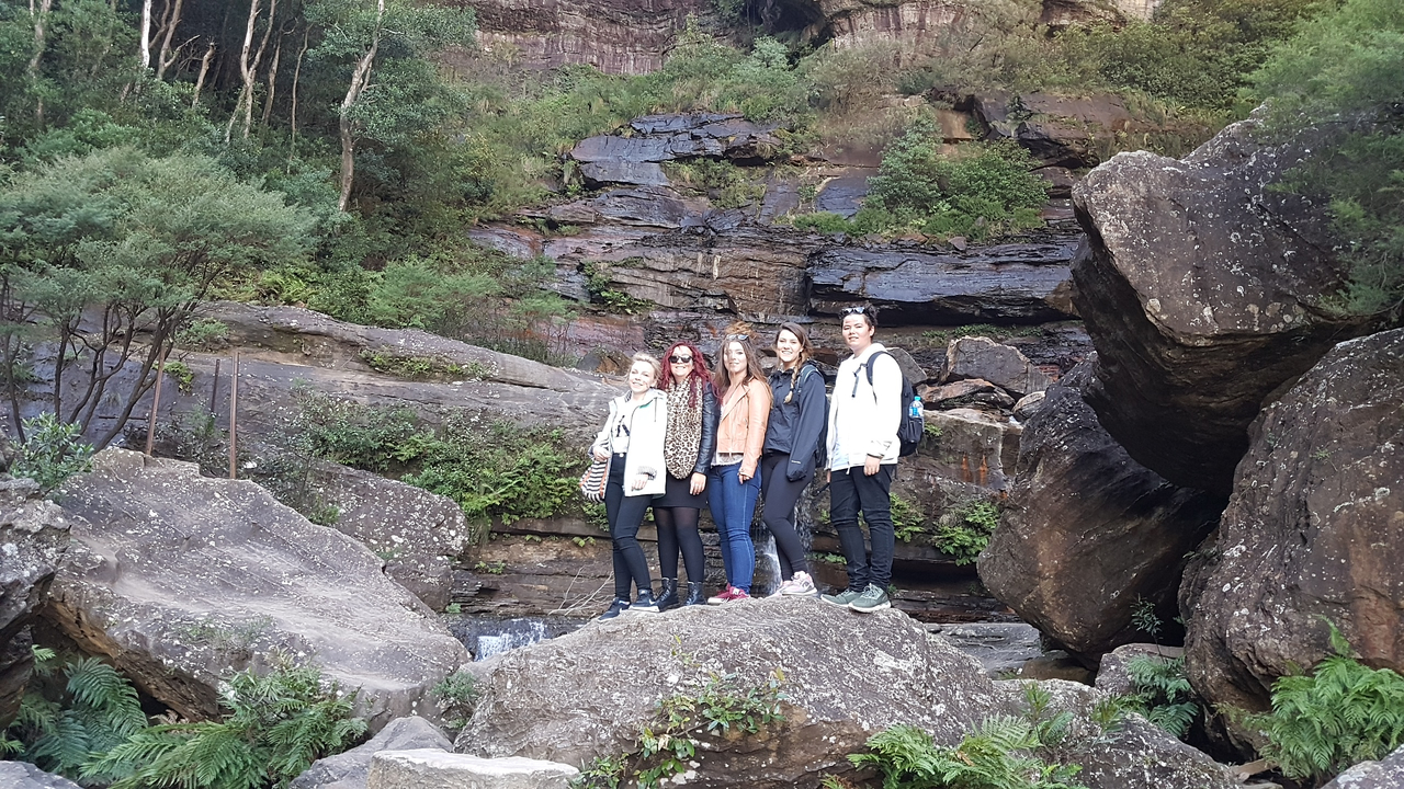 Group of people standing on rocks with earthy background.