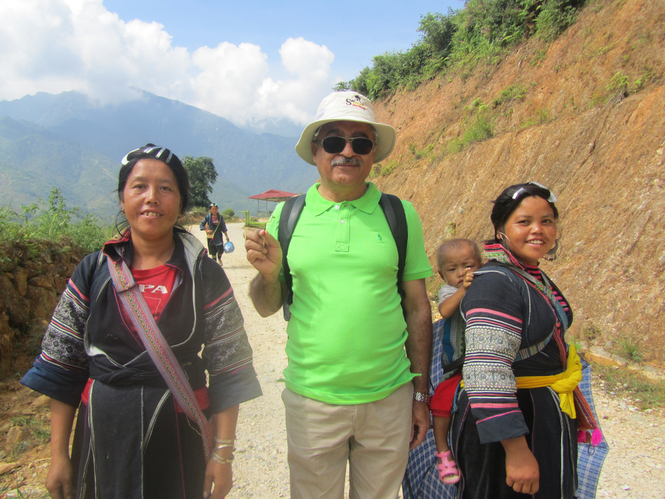 Un homme posant avec des habitants de la région sur un sentier de montagne.