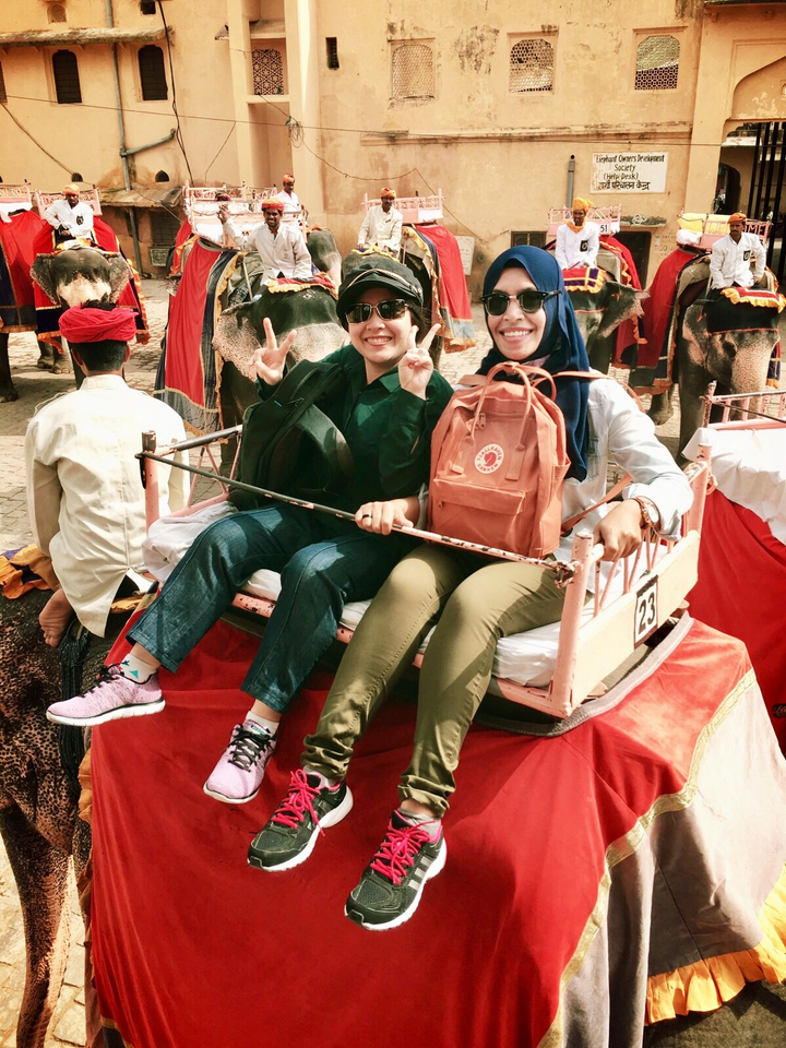 Deux femmes souriantes avec un signe de paix, assises sur une plate-forme.