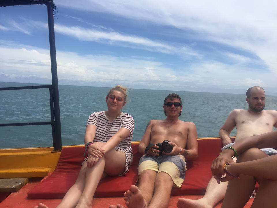 Two men and a woman relaxing on a boat with a camera.