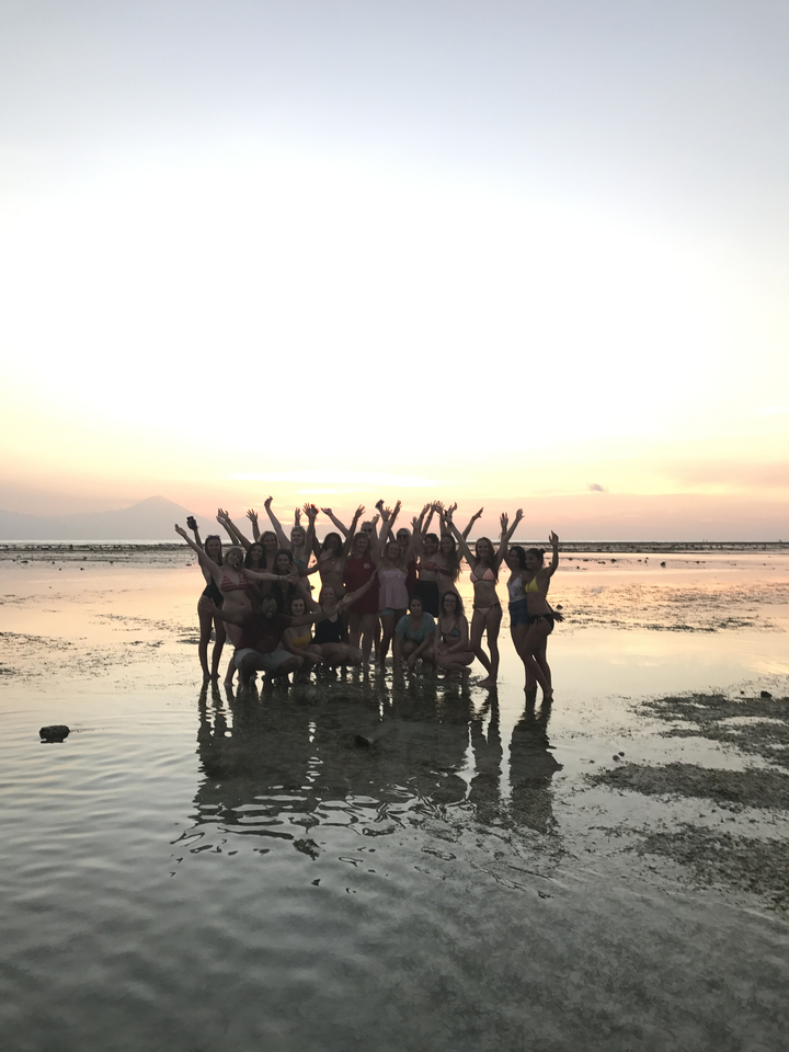 Group of people on a beach during sunset.