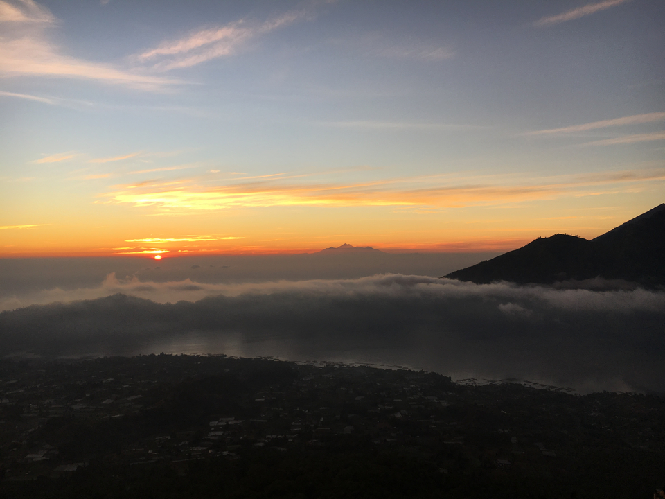 A sunrise over a lake with mountains silhouetted in the background.