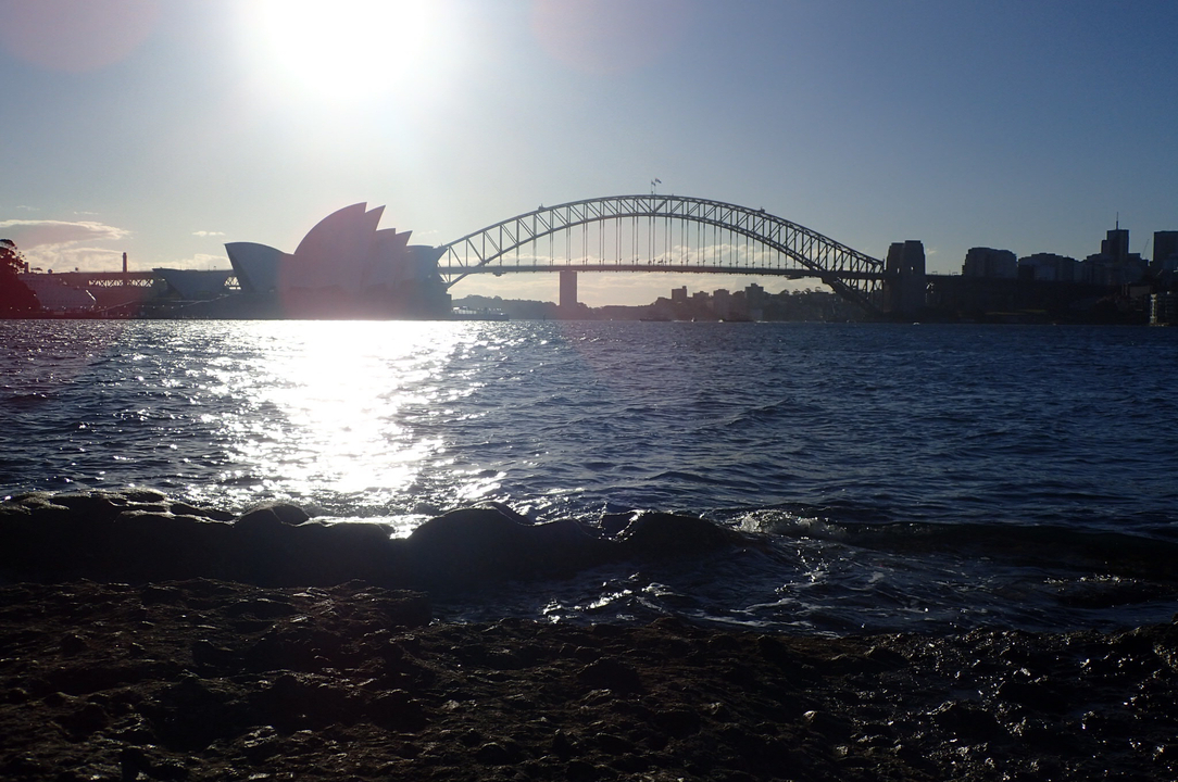 Sydney Opera House and Harbour Bridge at sunset over water.