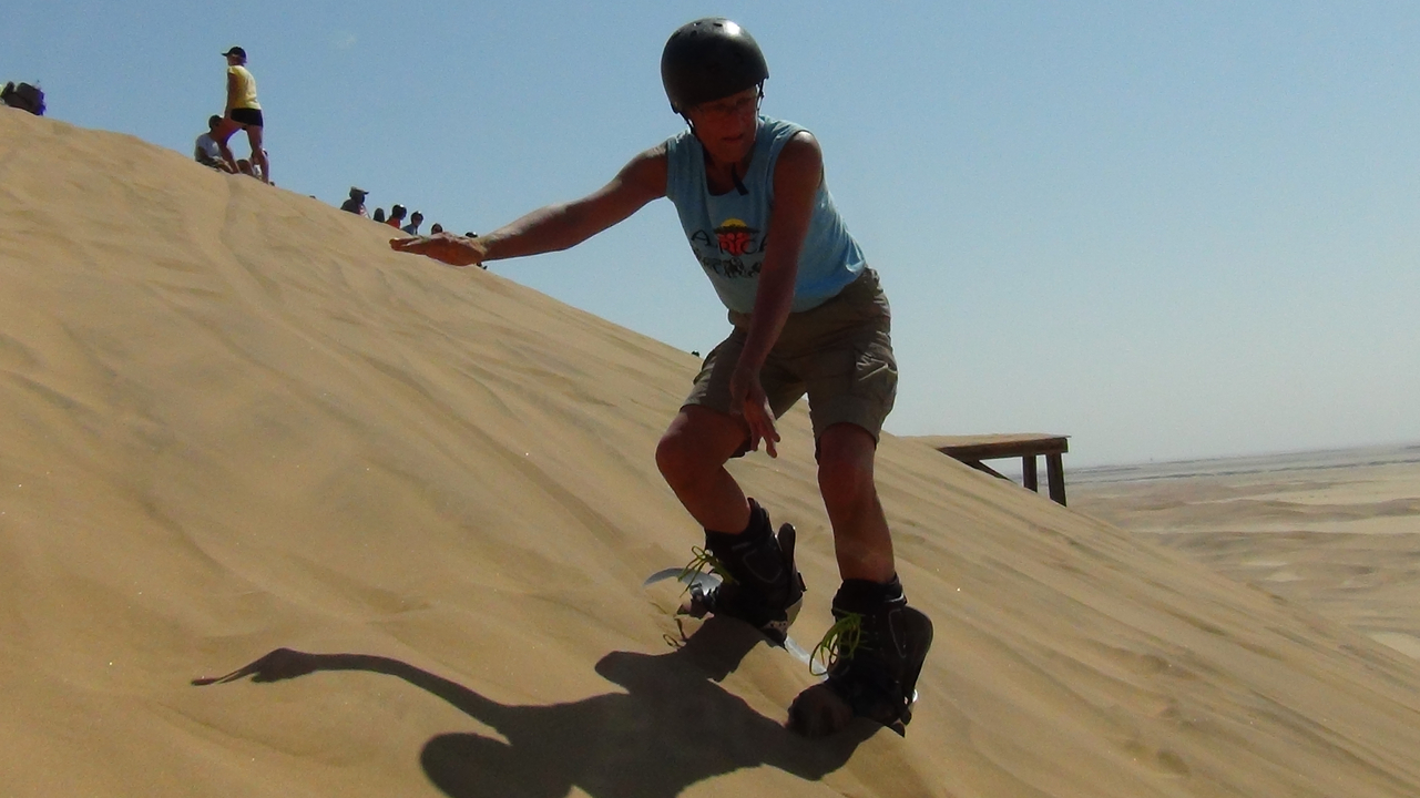 Personne faisant du sandboarding sur une dune.