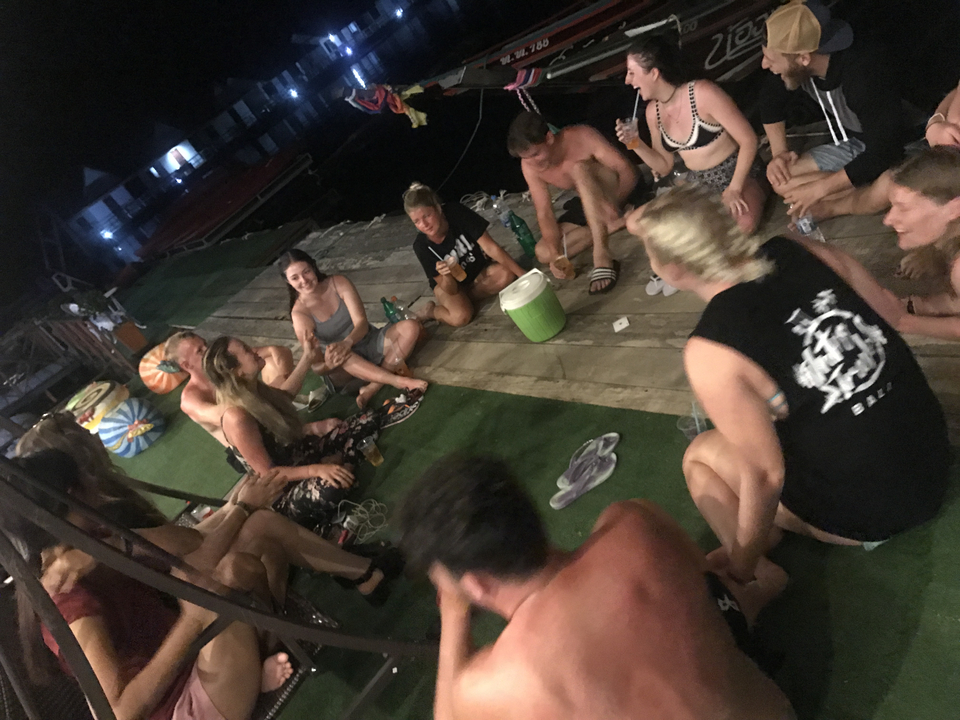 Group of people sitting and having drinks on a dock.