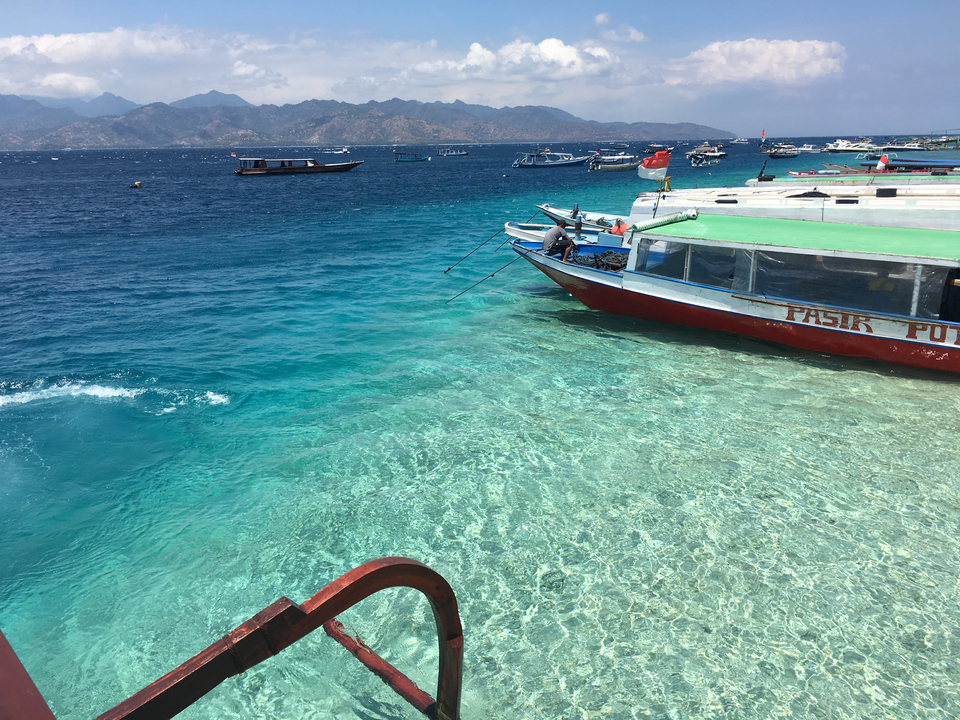 Clear turquoise water with boats anchored nearby.