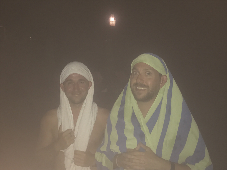 Deux hommes avec des serviettes autour de la tête dans un décor sombre.