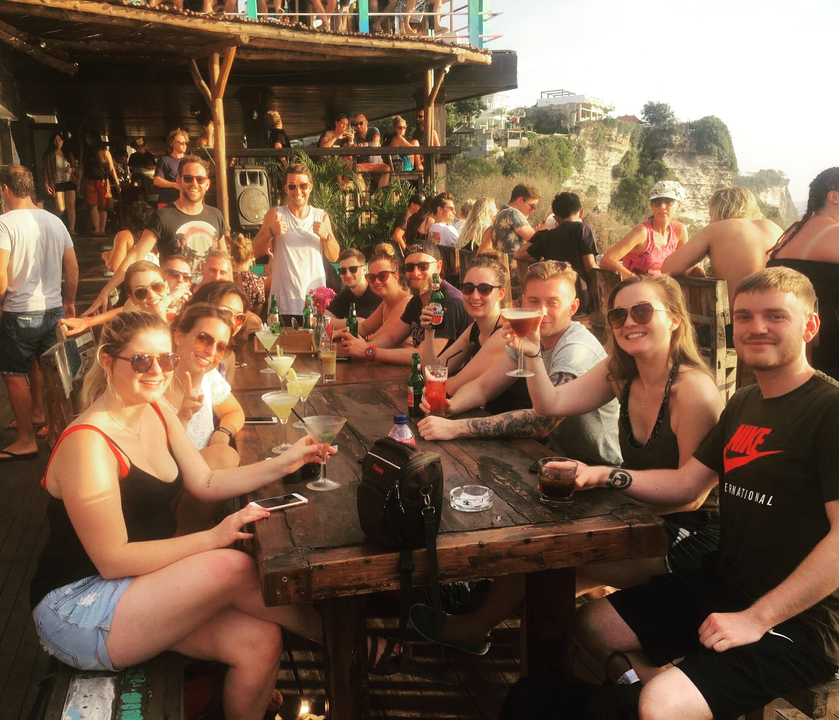 Un grand groupe de personnes assises à une longue table avec des boissons, souriant à la caméra.