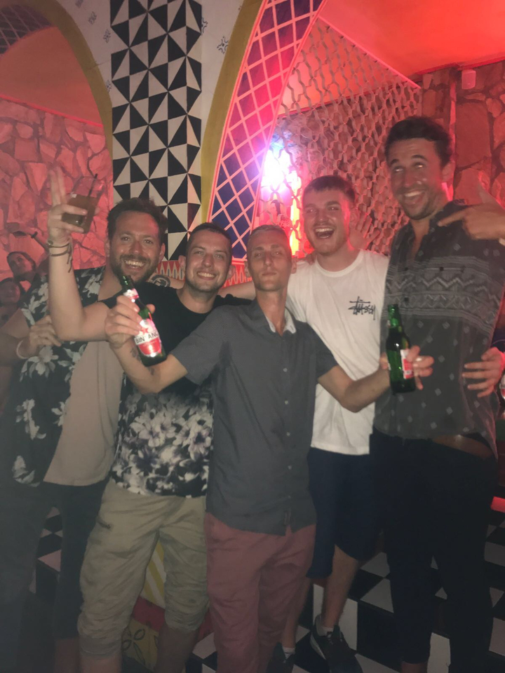 Groupe d'hommes posant et tenant des boissons dans ce qui semble être un club.