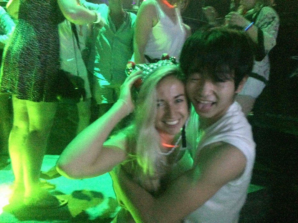 A couple embracing on a crowded dance floor with dim lighting.