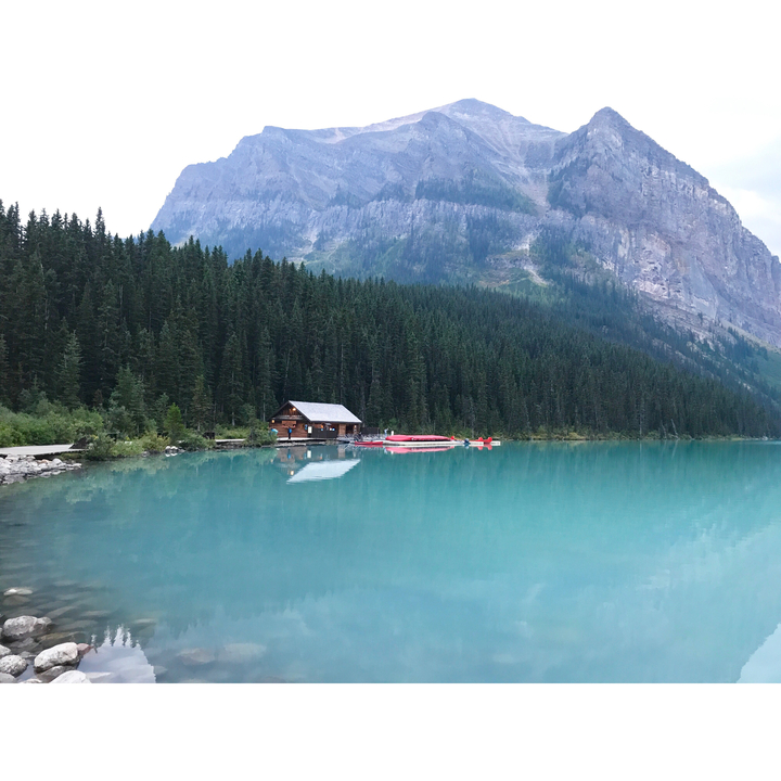 Hütte am See mit Kanus auf einem spiegelglatten See.