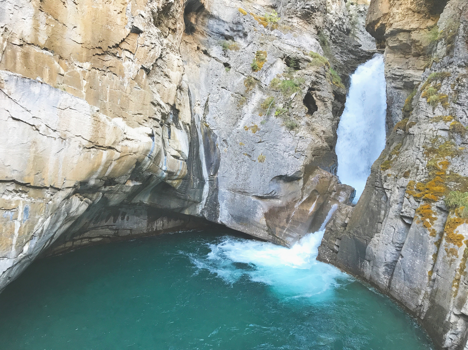 Ein Wasserfall, der in einen türkisfarbenen Pool stürzt.