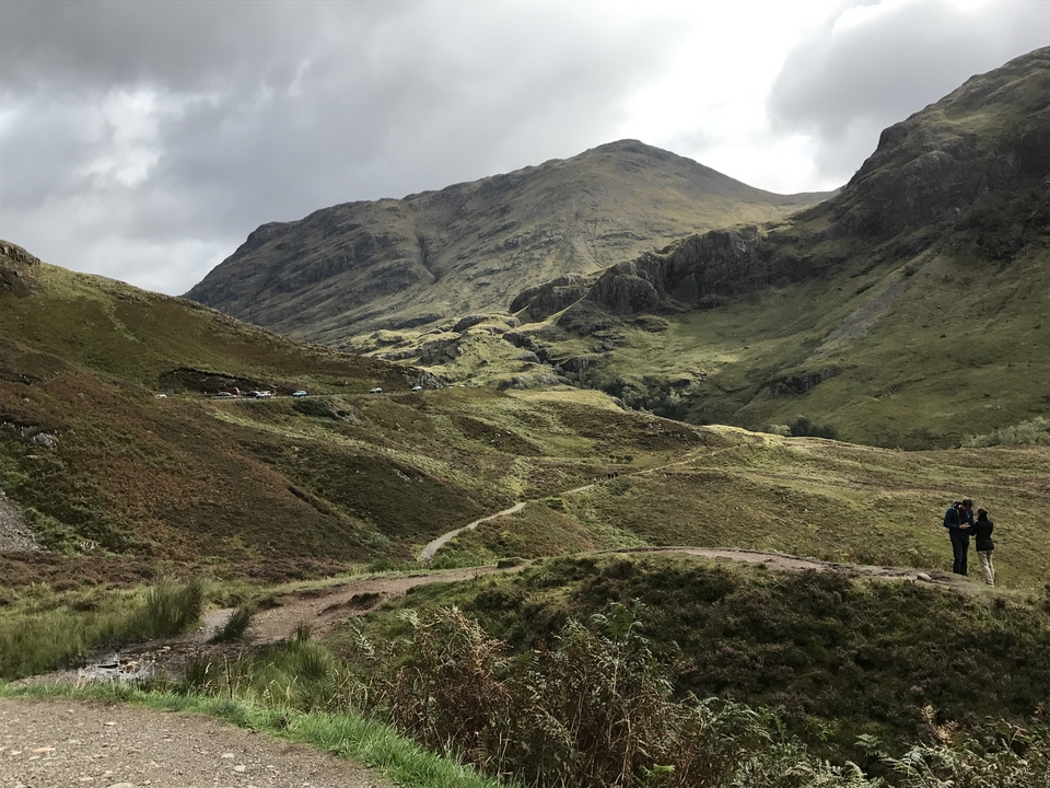 Chemin de randonnée dans une vallée verdoyante avec des montagnes.