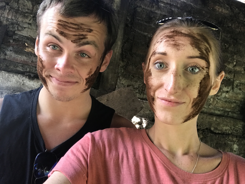 Two people with traditional clay on their faces smiling.